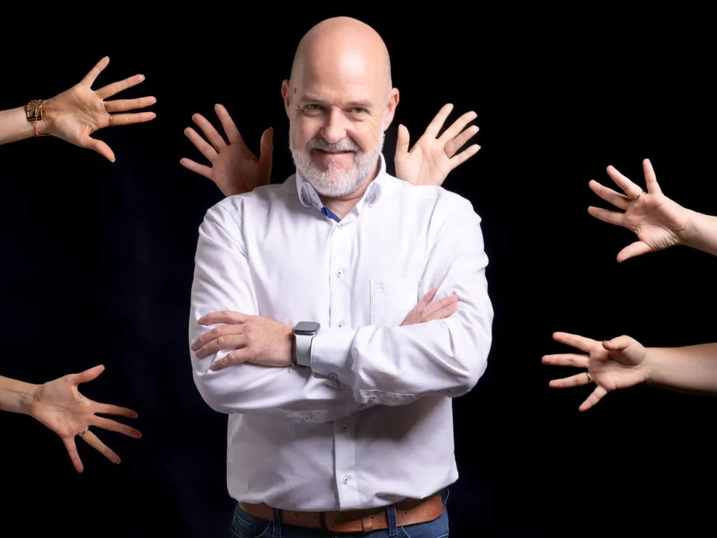 Johannes vor einem schwarzen Hintergrund und Hände kommen von jeder Seite ins Bild - kostenloses Erstgespräch mit Werbeagentur EINSigartig buchen